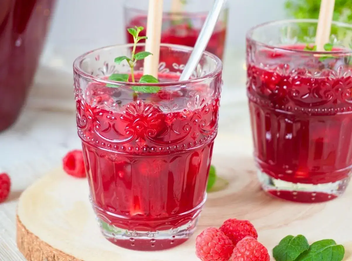 Erfrischende alkoholfreie Bowle mit Himbeeren und Minze in dekorativen Gläsern.