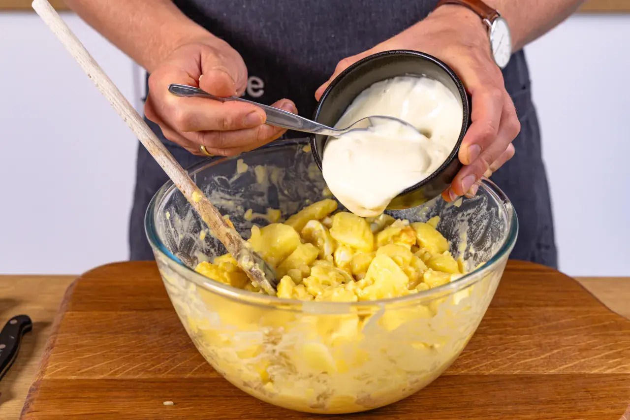 Hände geben Mayonnaise zu Kartoffeln für norddeutschen Kartoffelsalat.