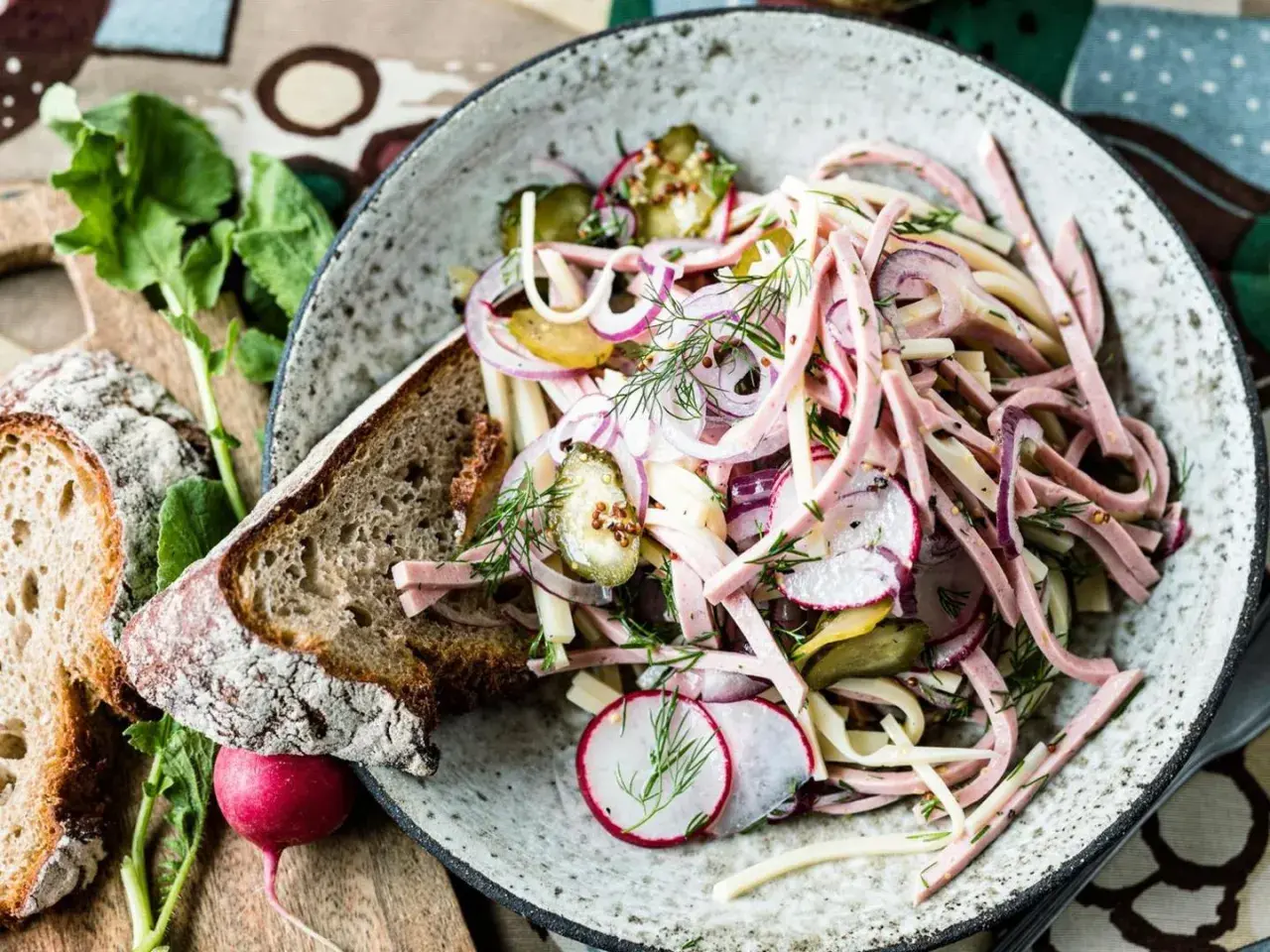 Ein bayerischer Wurstsalat, garniert mit Radieschen, Zwiebeln und Dill, serviert mit Bauernbrot.