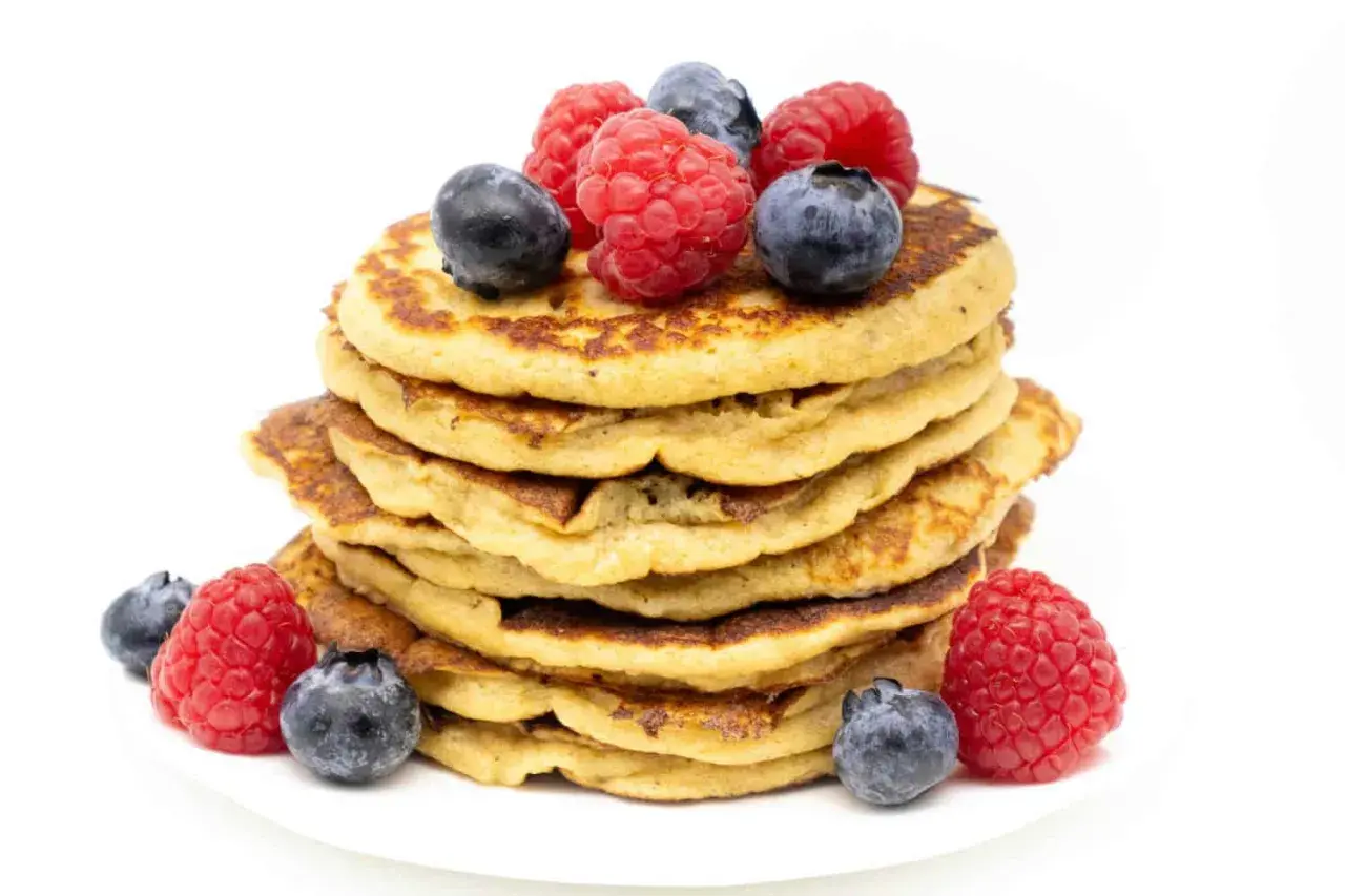 Stapel zuckerfreier Bananen-Pancakes, garniert mit frischen Himbeeren und Blaubeeren. Ein gesunder Genuss!