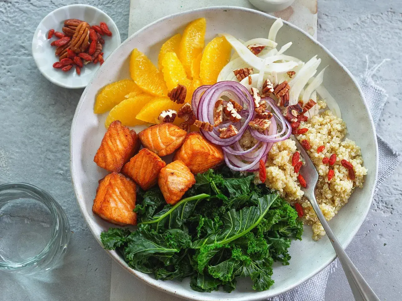 Gesunde Bowl-Rezepte: Lachs, Grünkohl, Quinoa, Orange, Fenchel, rote Zwiebeln, Pekannüsse und Goji-Beeren.