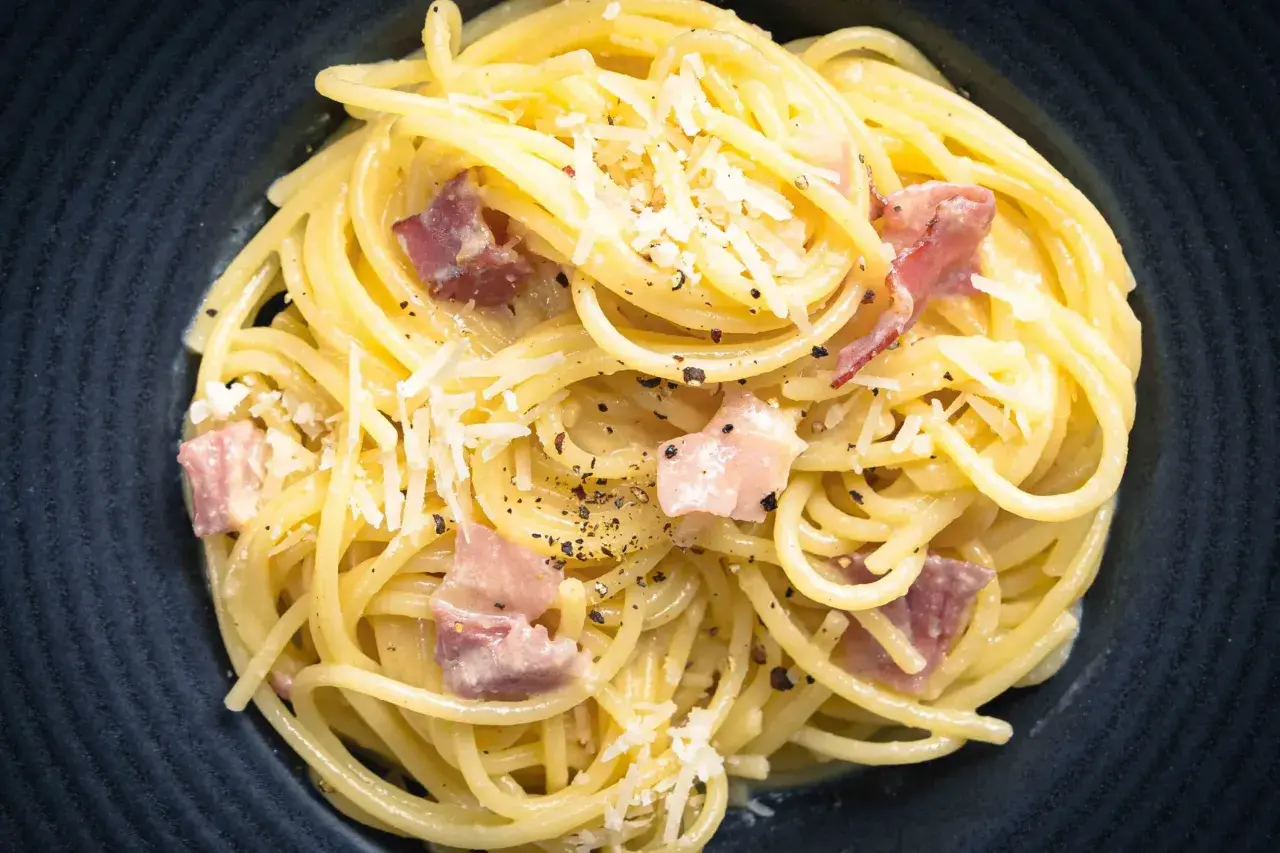 Spaghetti Carbonara mit Speck und Parmesan, ein Gericht, das leicht misslingt. Vermeiden Sie 10 Fehler beim Pasta kochen für perfekten Genuss.
