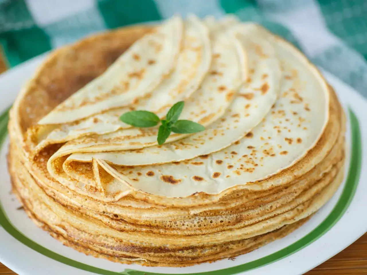 Ein Stapel goldbrauner Pfannkuchen, garniert mit Minze. Ein köstliches Pfannkuchen-Rezept, das zum Genießen einlädt.