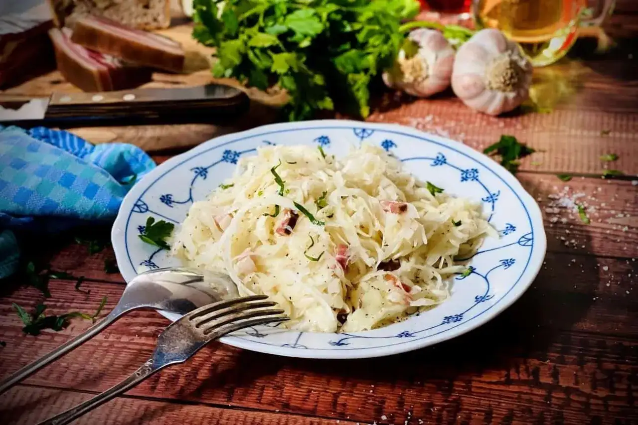 Ein Teller mit Krautsalat, garniert mit Petersilie. Perfekt für ein einfaches Krautsalat Rezept mit Speck und Brot.