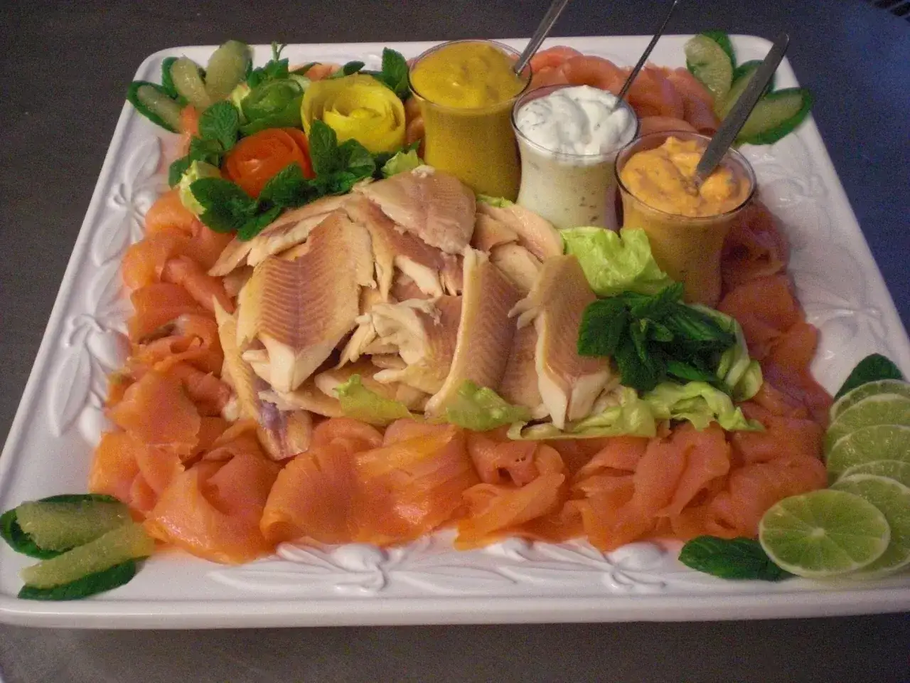 Eine festliche Fischplatte mit R&auml;ucherlachs, pochiertem Fisch, Dips und Limettenspalten. Perfekt, um eine Fischplatte selber zu machen!