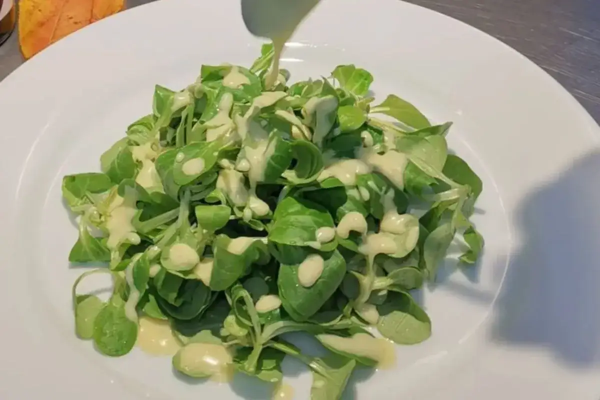 Frischer Feldsalat wird mit einem cremigen Kartoffeldressing betr&auml;ufelt.