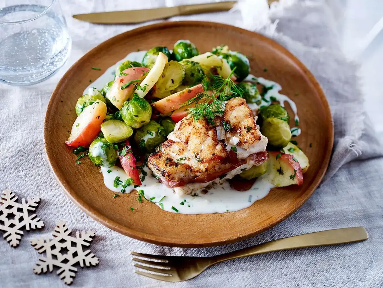Gebratener Fisch mit Rosenkohl und Apfelspalten auf cremiger Sauce, ein festliches Gericht f&uuml;r Fischgerichte Weihnachten.