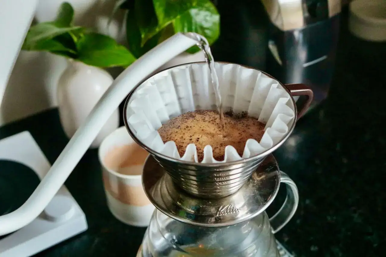 Hei&szlig;es Wasser flie&szlig;t langsam auf frisch gemahlenen Kaffee, um Filterkaffee zu kochen. Ein sch&ouml;ner Morgen beginnt.
