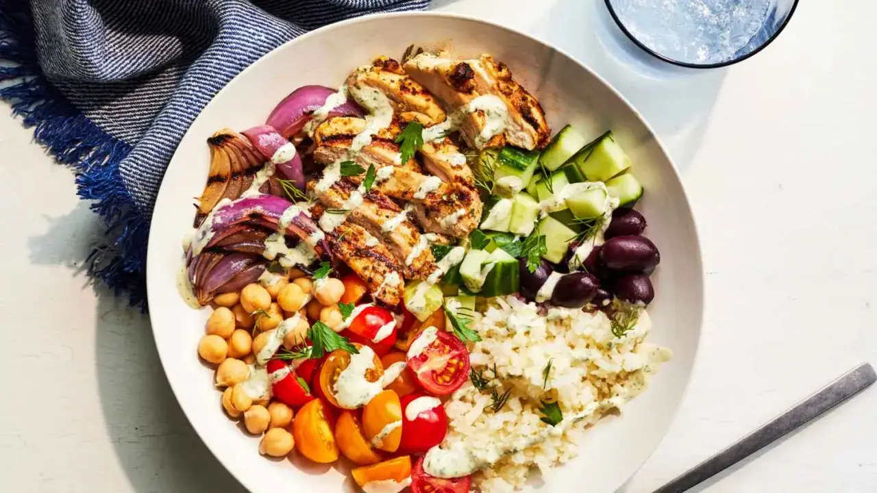 Herzhafte Bowl mit gegrilltem Hähnchen, Kichererbsen, Tomaten, Gurken, Oliven, Zwiebeln und Reis. Tolle Bowl Rezepte für ein gesundes Mittagessen.