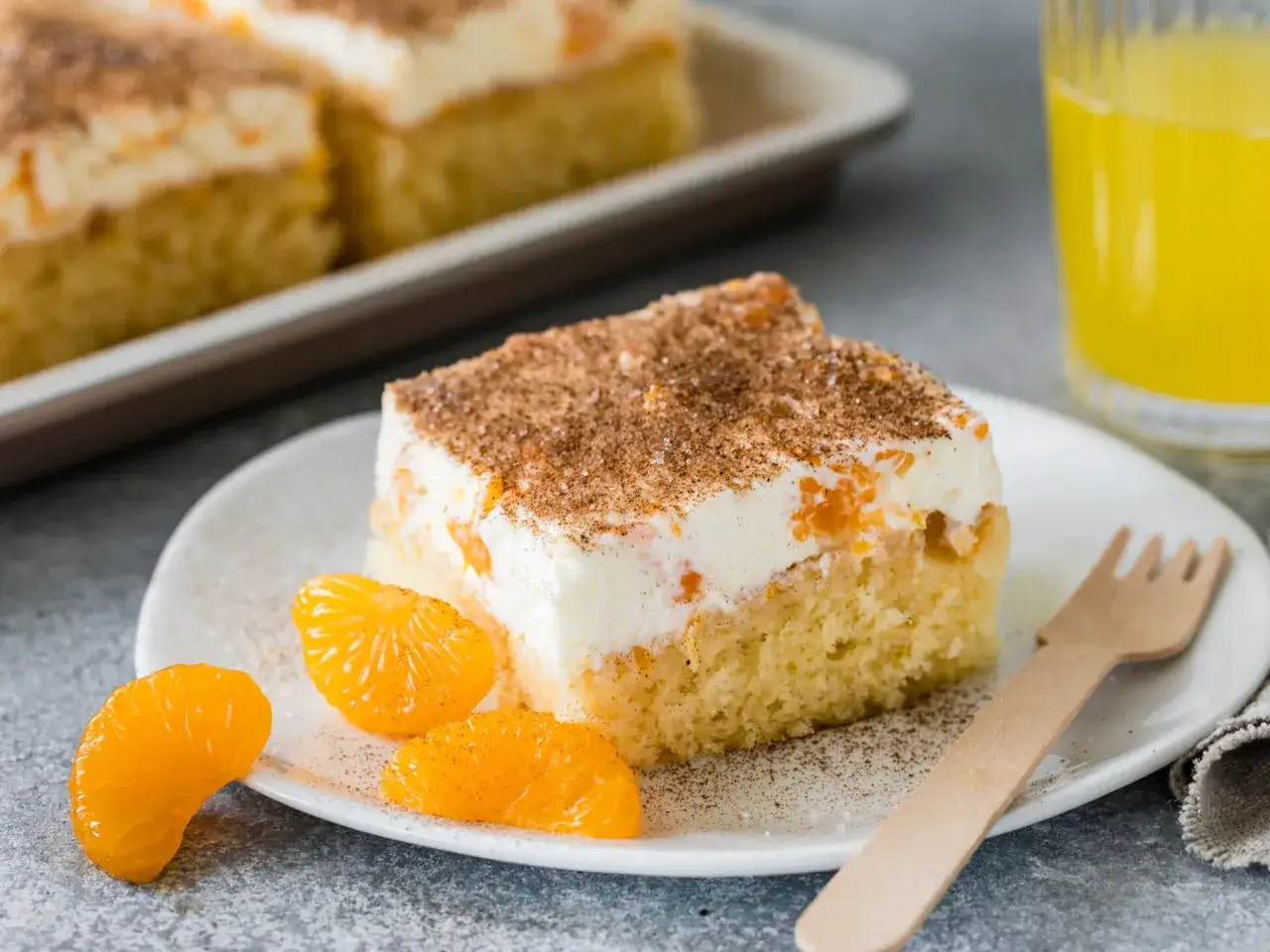 Ein St&uuml;ck von Omas Schmandkuchen vom Blech, bestreut mit Zimt und Zucker, garniert mit Mandarinenst&uuml;cken.