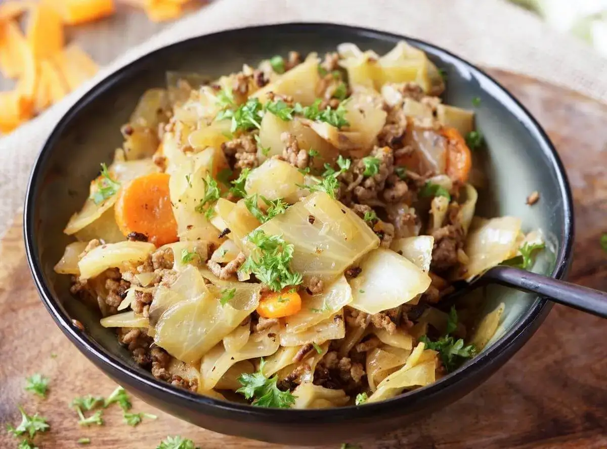 Herzhafte spitzkohl rezepte mit hackfleisch und Karotten, garniert mit frischer Petersilie, serviert in einer Schüssel.