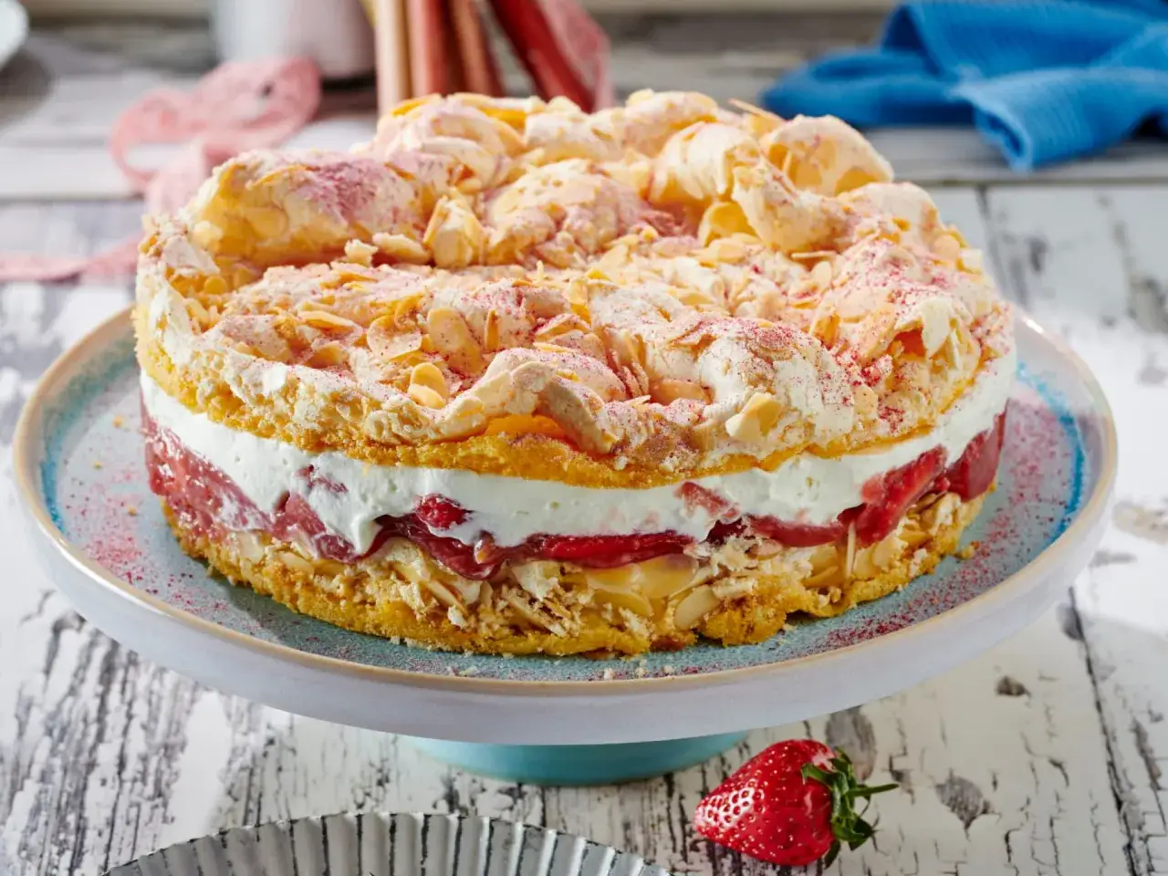 Ein köstlicher Rhabarberkuchen mit Baiser, wie ihn Landfrauen backen. Mit Mandelblättchen und Puderzucker bestreut.