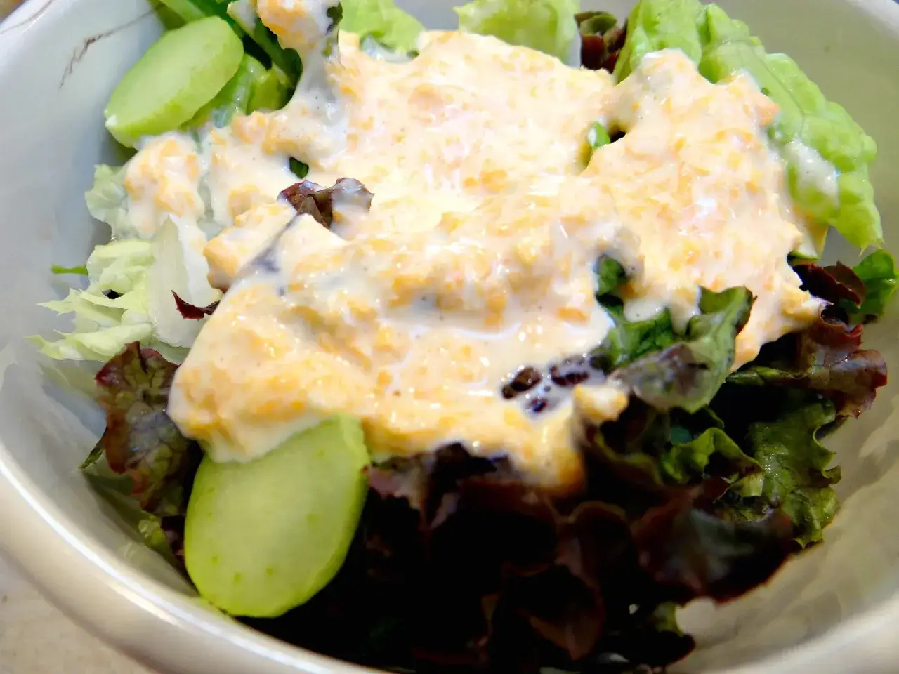 Frischer Salat mit cremigem salatdressing wie im restaurant. Gurkenscheiben und verschiedene Blattsalate sind mit einer k&ouml;stlichen, orangenfarbenen Sauce &uuml;berzogen.