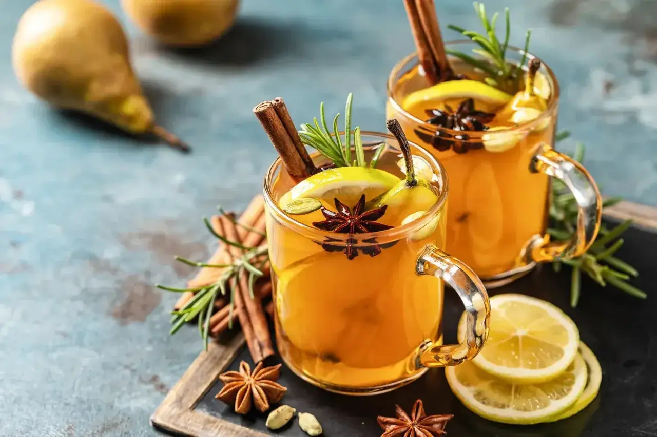 Zwei Gl&auml;ser mit einem warmen Hot Toddy, garniert mit Zimt, Sternanis, Zitrone und Birne. Perfekt f&uuml;r ein Hot Toddy Rezept.