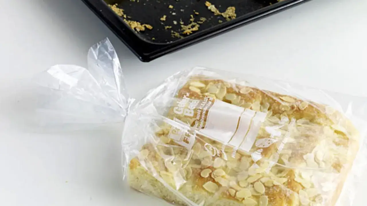 Ein mit Mandeln bestreuter Kuchen, verpackt in einer Plastikt&uuml;te, bereit zum Kuchen einfrieren. Daneben eine leere Backform.