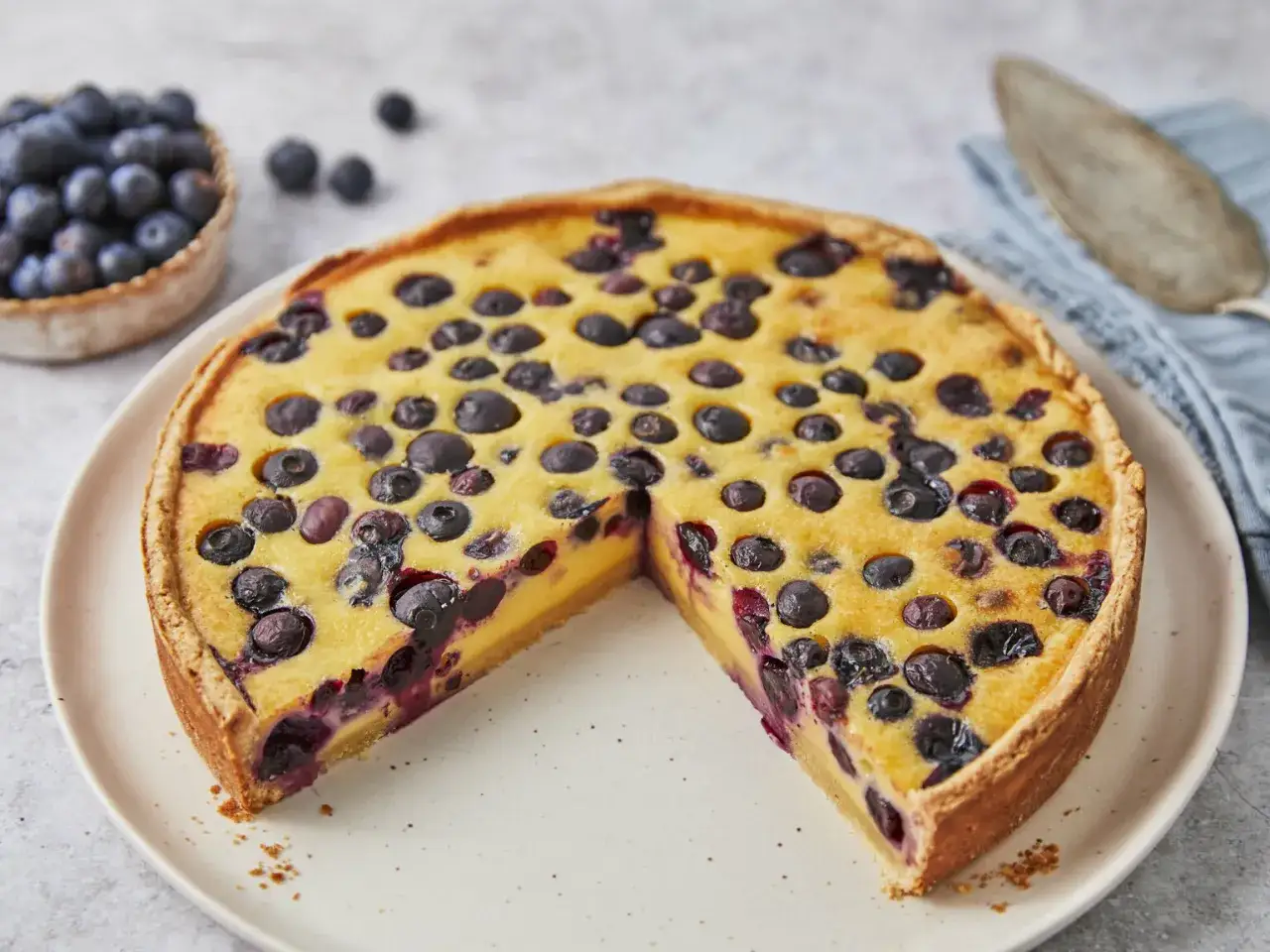 Ein k&ouml;stlicher Heidelbeerkuchen mit Vanillepudding, belegt mit frischen Blaubeeren. Ein St&uuml;ck fehlt bereits.