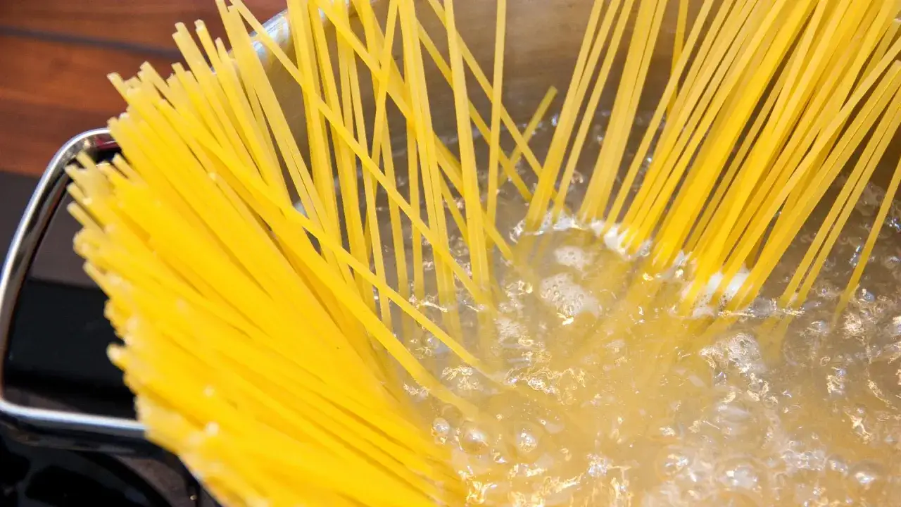 Spaghetti kochen in sprudelndem Wasser. Die gelben Nudeln werden langsam weich.