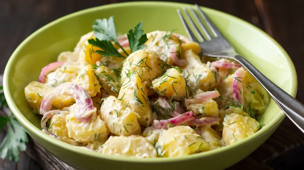 Schwedischer Kartoffelsalat mit Matjes, cremiger Kartoffelsalat mit roten Zwiebeln und Dill, garniert mit Petersilie.