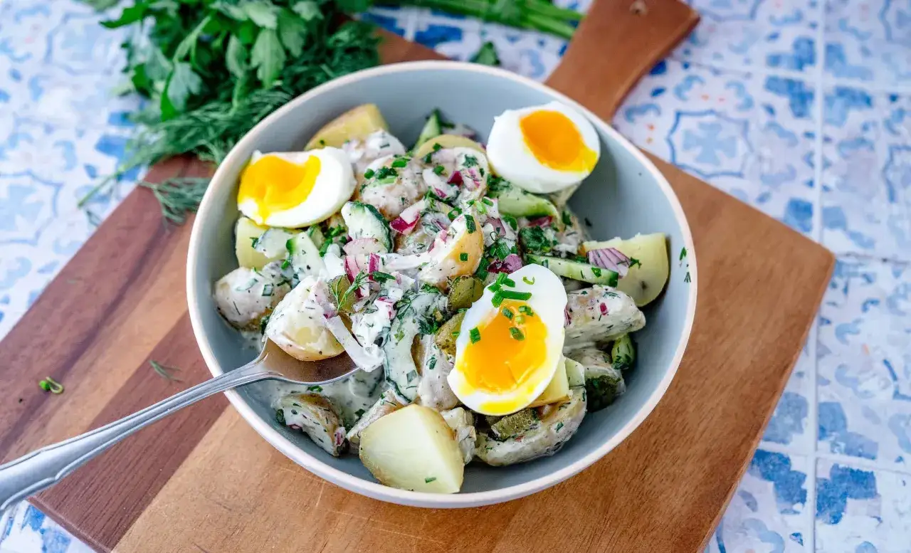 Ein norddeutscher Kartoffelsalat mit gekochten Eiern, Gurken und frischen Kräutern in einer cremigen Sauce.
