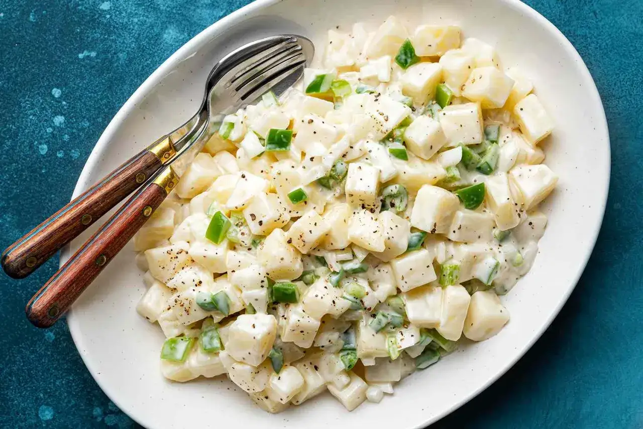 Cremiger Kartoffelsalat mit gr&uuml;nen Paprikaw&uuml;rfeln und einem k&ouml;stlichen Kartoffel Dressing, serviert mit Besteck.