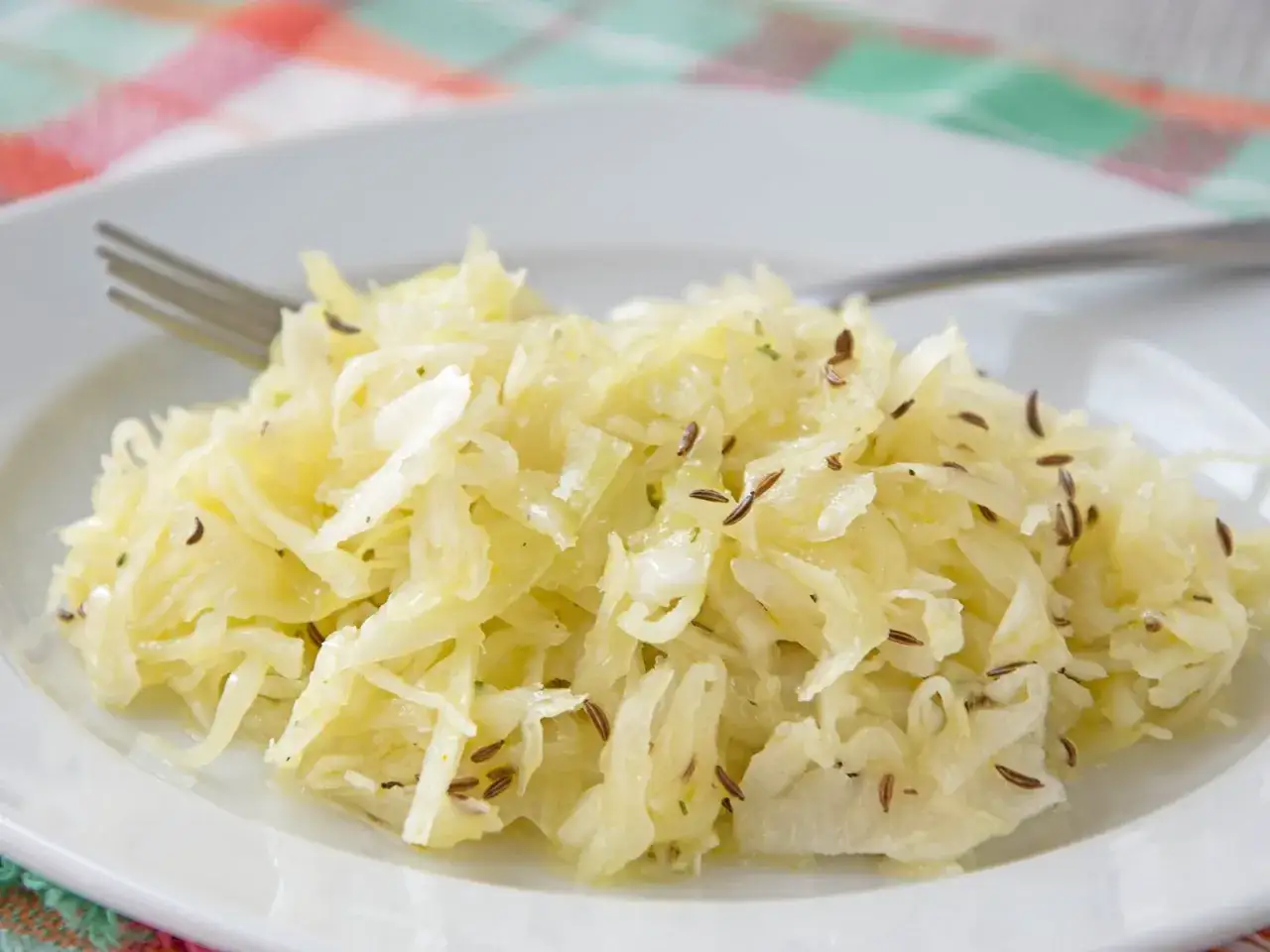 Ein Teller mit leckerem Krautsalat, perfekt für ein deftiges krautsalat rezept. Mit Kümmel verfeinert und bereit zum Genießen.