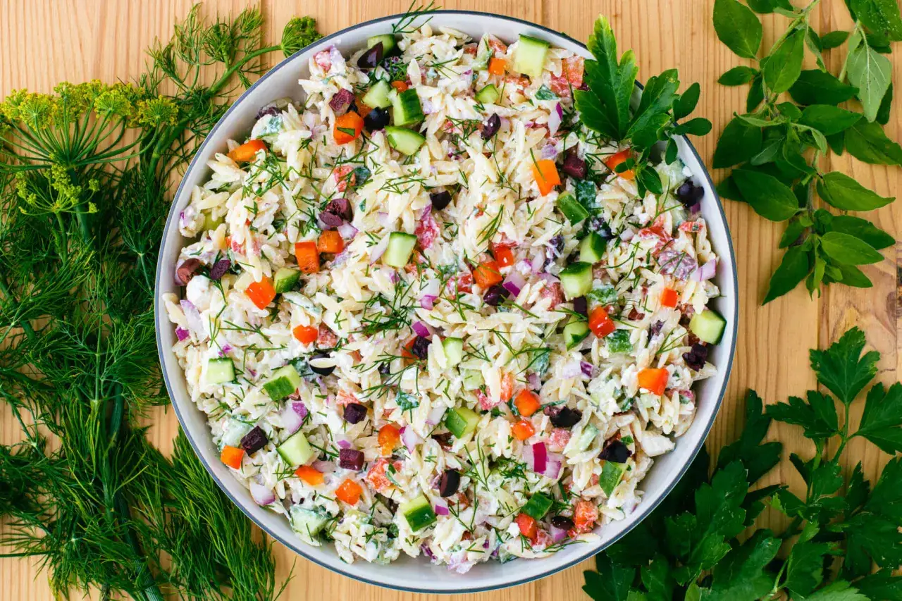 Frischer Kritharaki Salat mit Gurken, Tomaten, Paprika und Oliven, garniert mit Dill und Petersilie.