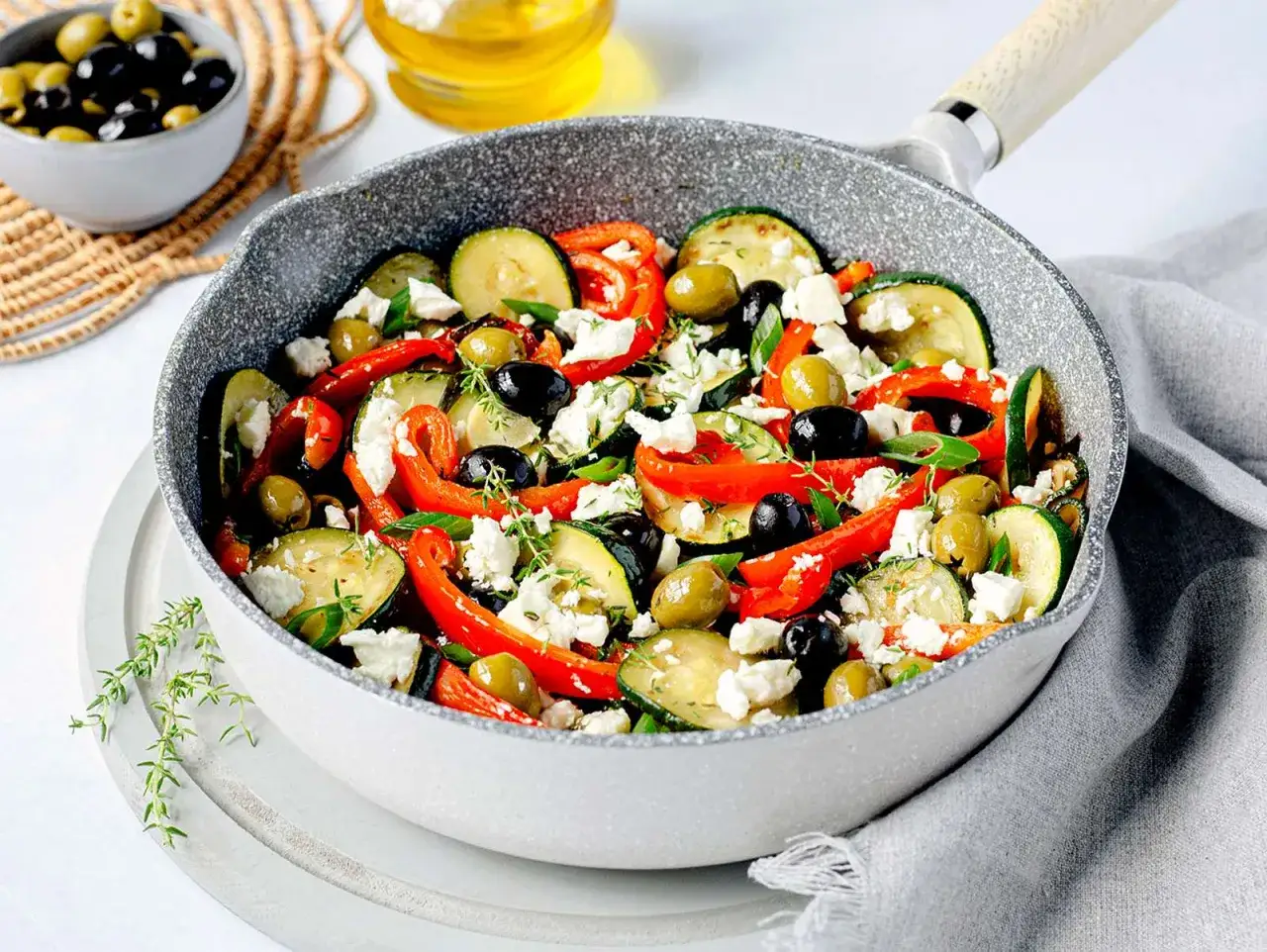 Bunte zucchini pfanne mit Paprika, Oliven und Feta, garniert mit frischen Kräutern.