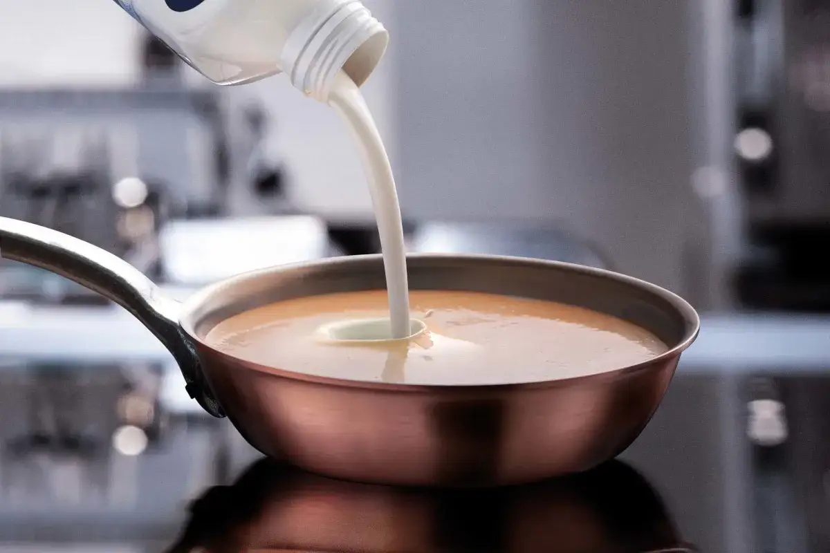 Sahne zum Backen wird in eine Pfanne gegossen, um eine cremige Sauce zuzubereiten.