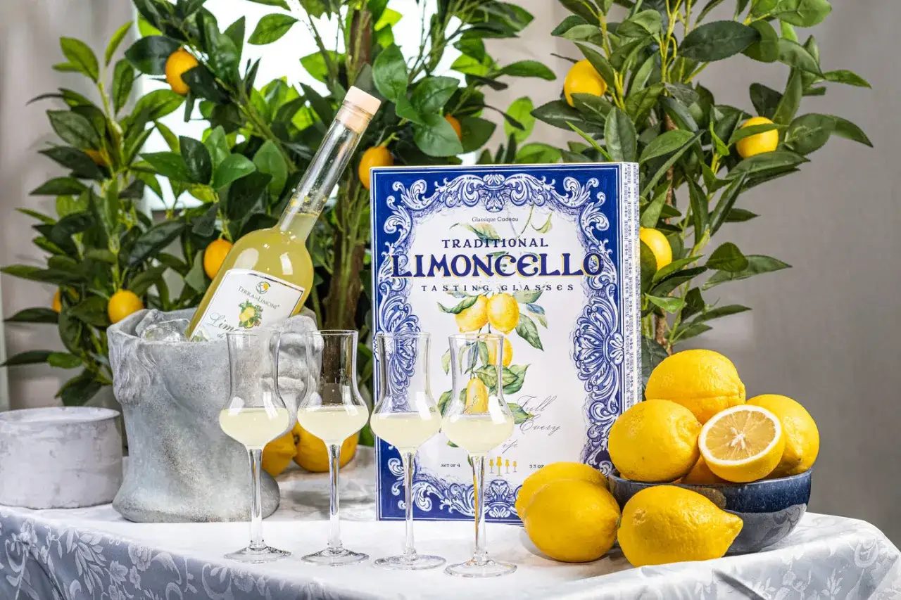 Limoncello wie trinken? Ein eisgekühlter Likör in eleganten Gläsern, umgeben von Zitronen und grünen Blättern. Perfekt für den Genuss!