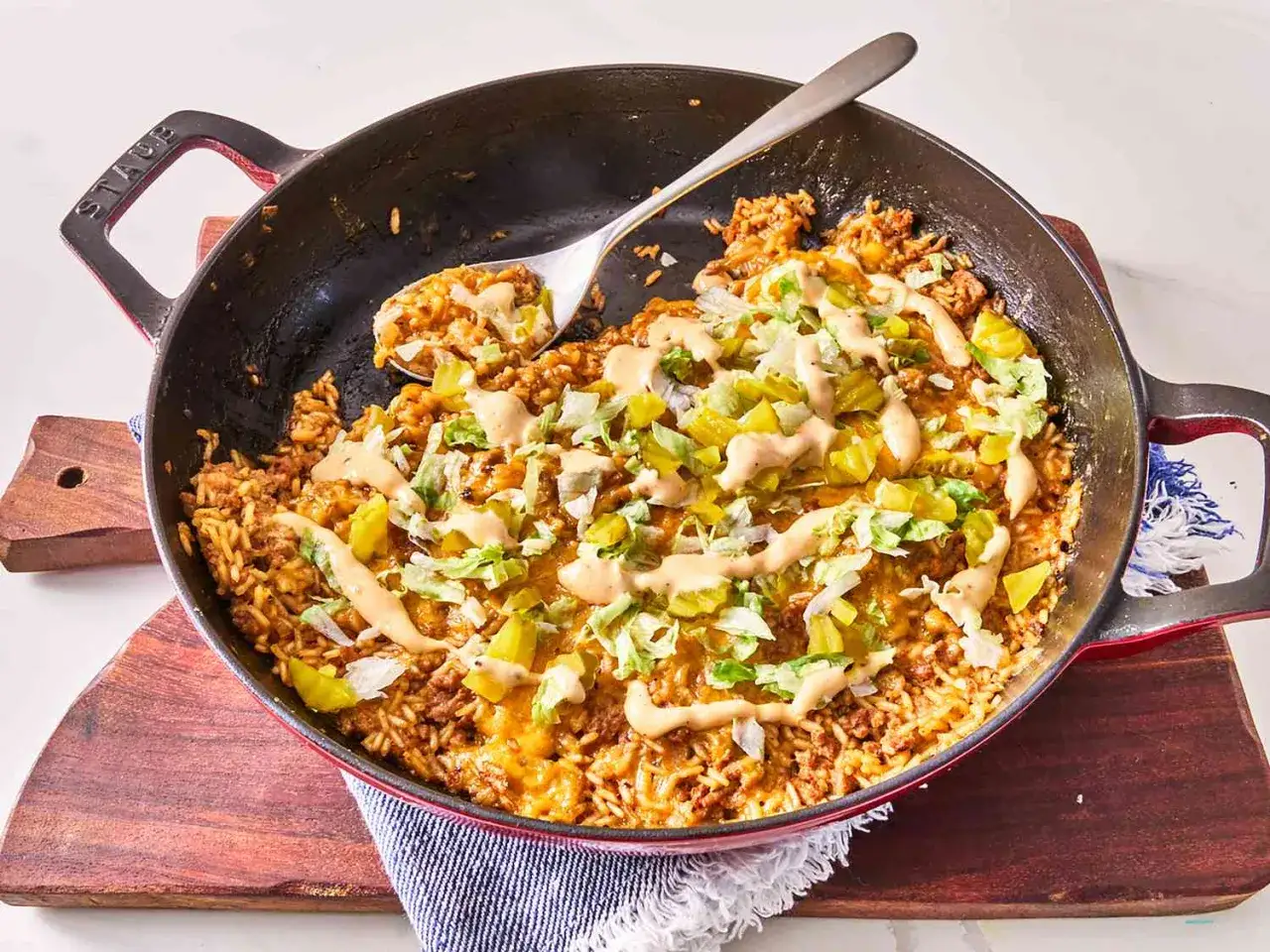 Herzhaftes Hackfleisch-Reis-Gericht in einer Pfanne, perfekt f&uuml;r schnelle Hackfleisch Rezepte. Mit K&auml;se, Salat und Sauce garniert.