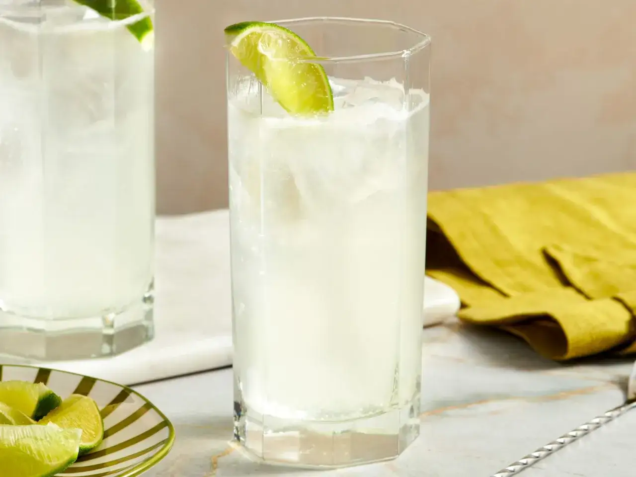 Erfrischende Gin Cocktails mit Limettenspalten, Eis und einem gelben Tuch.