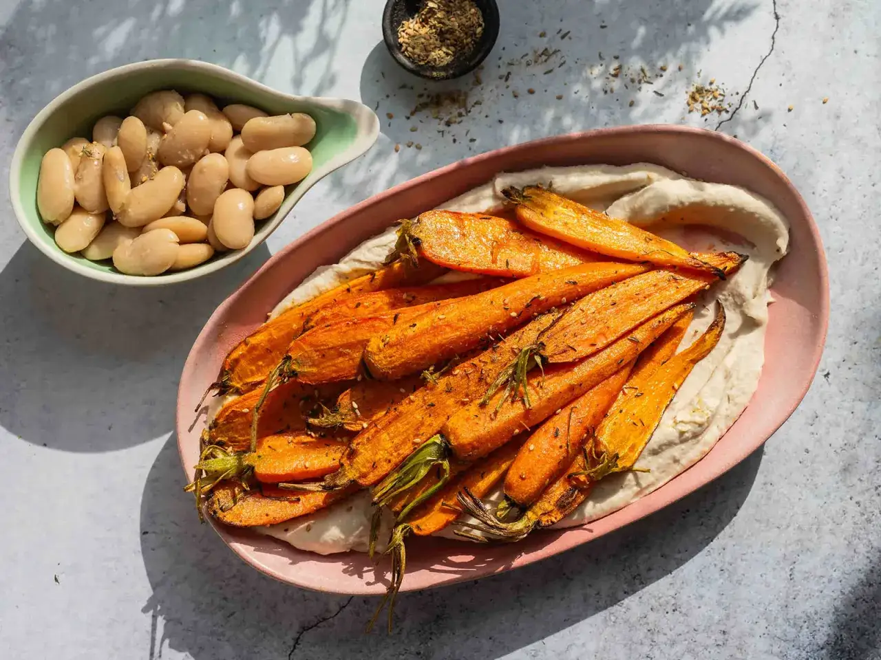 Geröstete Karotten auf Hummus, dazu weiße Bohnen. Perfekt für einfache Airfryer Rezepte.