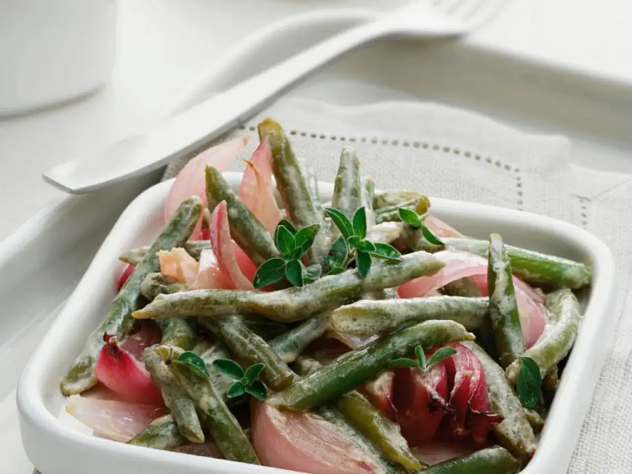 Gr&uuml;ne Bohnen mit roten Zwiebeln in cremiger Sauce, garniert mit Kr&auml;utern. Perfekt, wenn man wissen m&ouml;chte, wie lange Bohnen kochen.