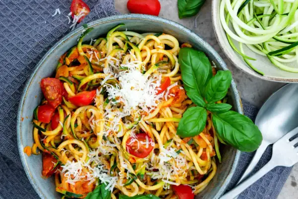 Herzhafte Zucchini-Nudeln mit Tomaten und Parmesan, garniert mit frischem Basilikum. Ein leichtes Gericht, das schmeckt.