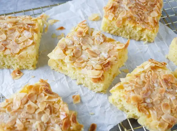 Omas saftiger Buttermilchkuchen, goldbraun gebacken und mit knusprigen Mandelblättchen bestreut, wartet darauf, genossen zu werden.