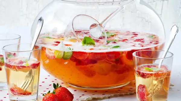 Erfrischendes Bowle-Rezept mit Erdbeeren und Minze in einer großen Glasbowle, bereit zum Servieren in Gläsern.