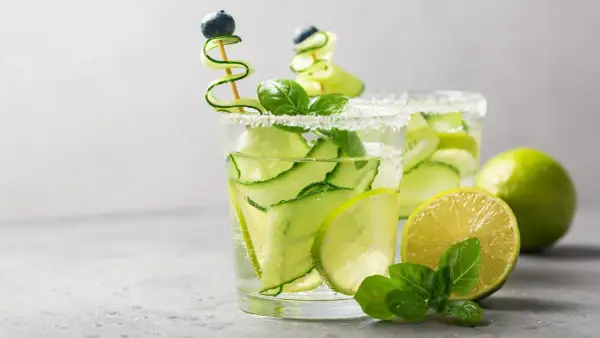 Zwei erfrischende Aperitifs mit Gurke, Limette und Minze, garniert mit Blaubeeren.