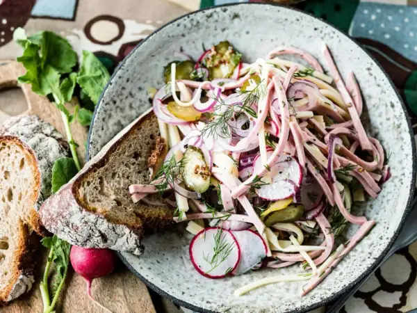 Ein bayerischer Wurstsalat, garniert mit Radieschen, Zwiebeln und Dill, serviert mit Bauernbrot.