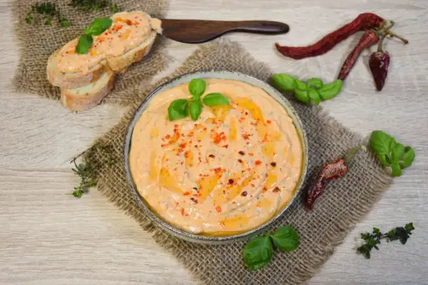 Cremiger Tomate Mozzarella Aufstrich mit Basilikum und Chili, serviert auf Baguette und in einer Schale.