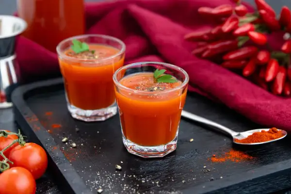 Zwei Gläser scharfer Tomatensaft, perfekt für ein mexikaner rezept. Mit frischen Tomaten und Chilis garniert.