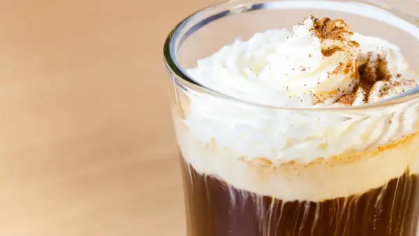 Ein erfrischender Eiskaffee mit Sahne und Zimt bestreut, perfekt für einen warmen Tag.